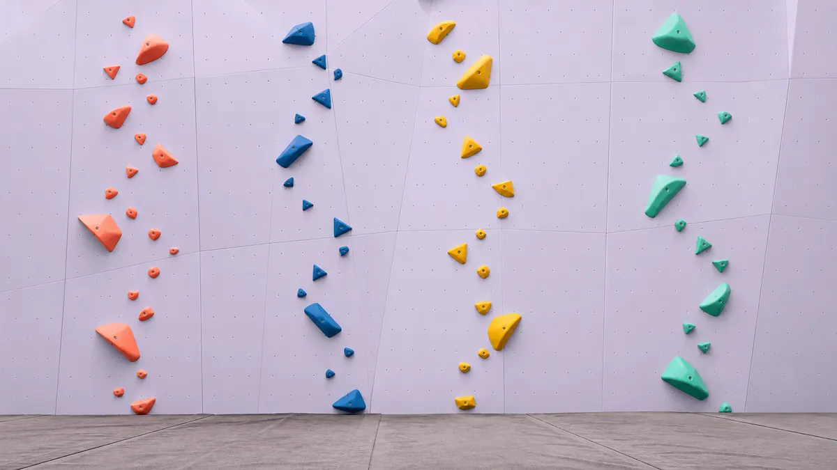 empty pale-lilac climbing wall with coral, blue, yellow, and mint routes