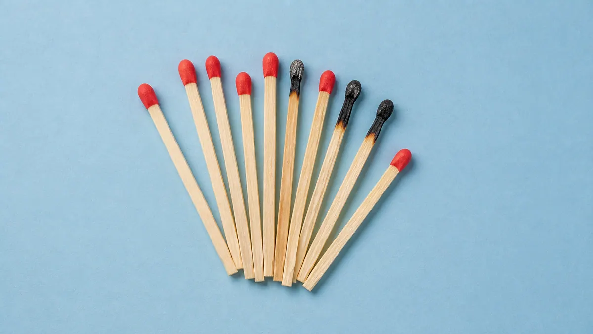 Intact vermilion matches and spent black matches fan across powder-blue paper.